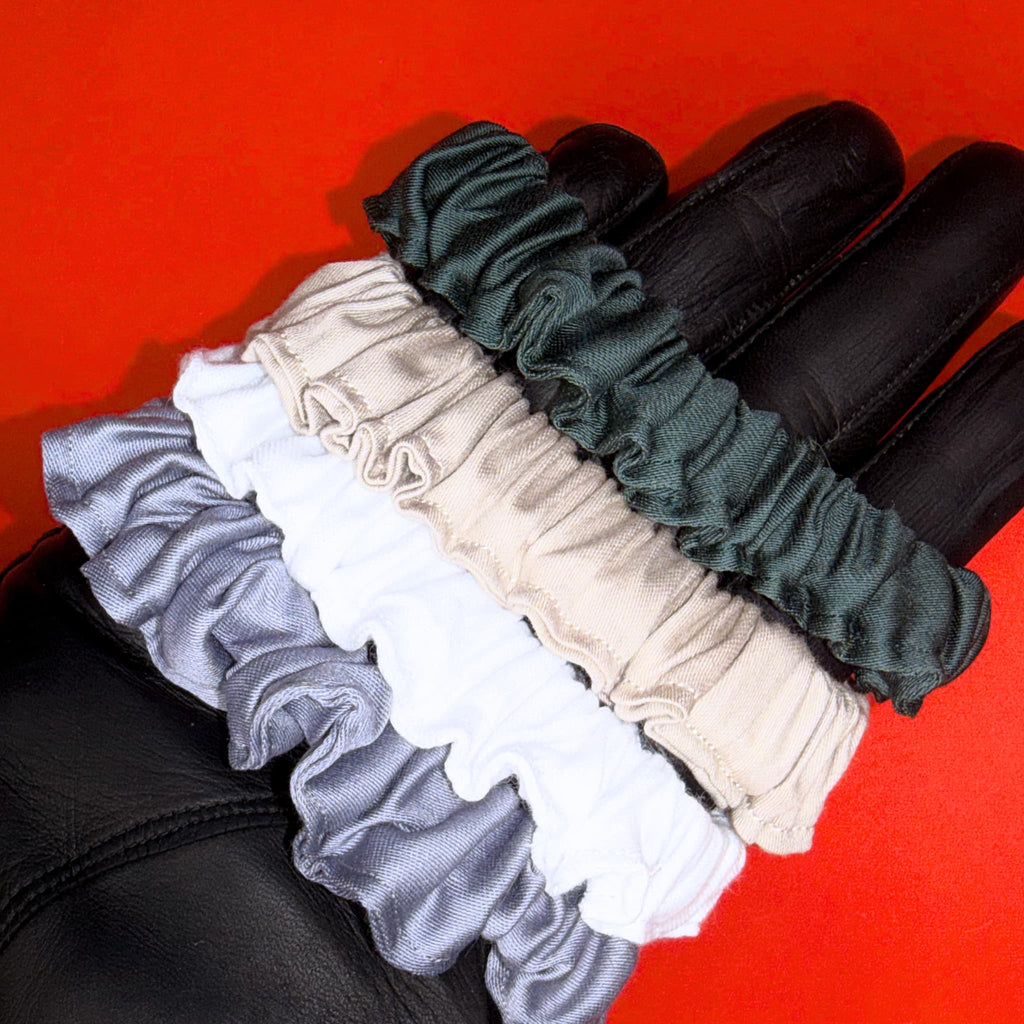 Scrunchie Mini od Hecatoo™ ve všech čtyřech barvách nasazené na ruce jako náramky – šedá, bílá, béžově zlatá a smaragdová. Gumička do vlasů i elegantní doplněk na zápěstí.