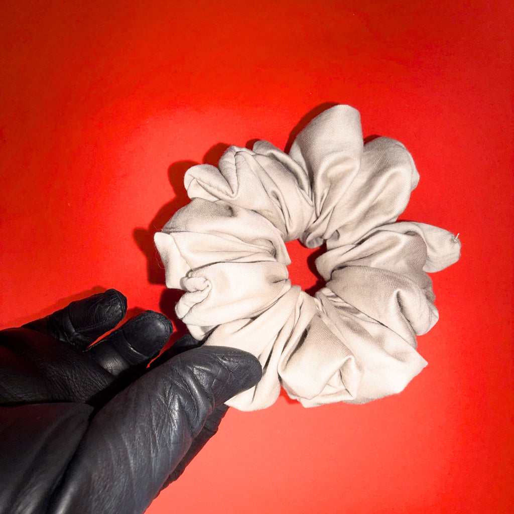 Béžově zlatá Scrunchie Oversized Hecatoo™ v ruce – ukázka objemu handmade gumičky ze 100% bavlněného saténu. Podzimní luxus pro každý typ vlasů, bez polyesteru.