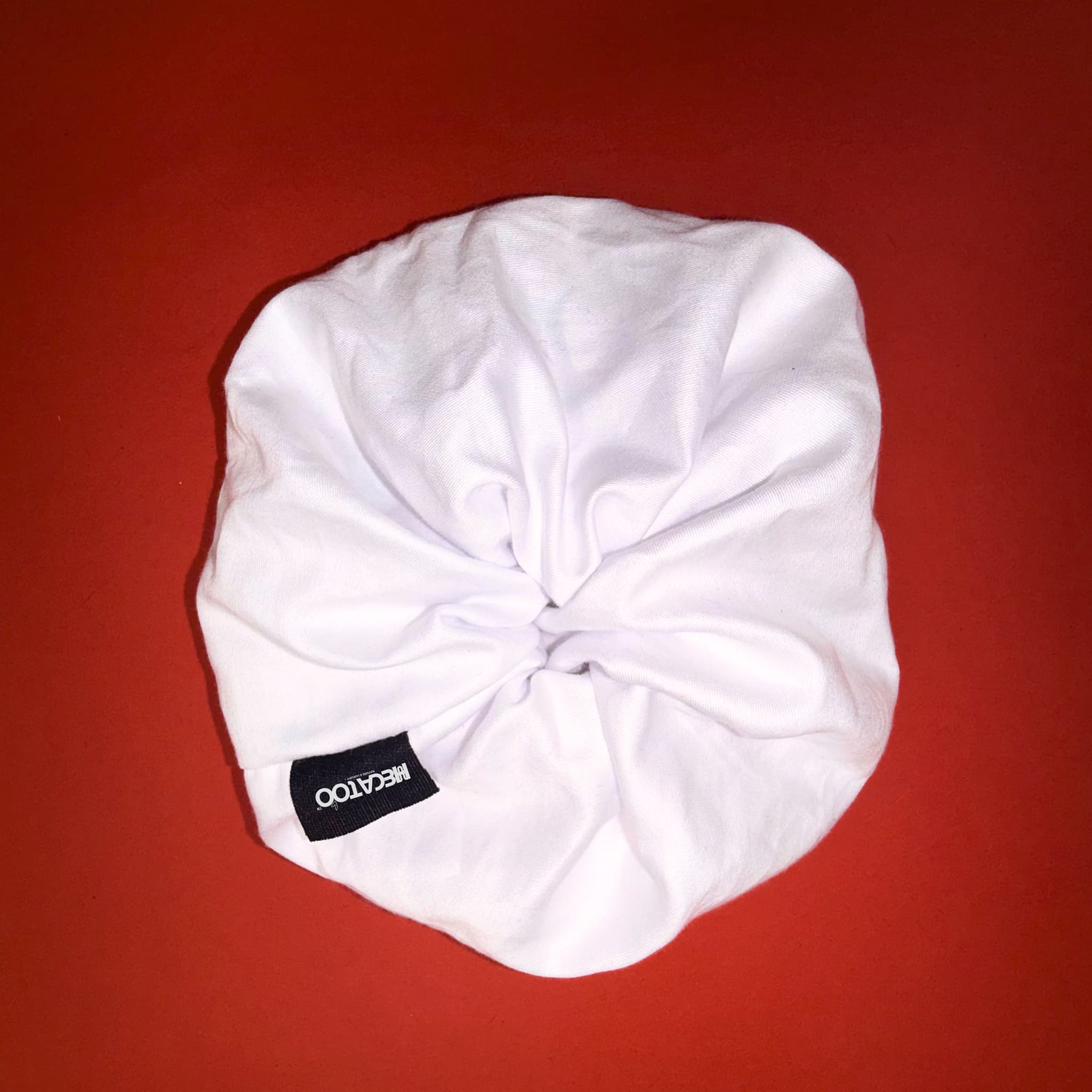 Bílá Scrunchie Oversized Smooth od Hecatoo™ v ruce – elegantní gumička do vlasů ze 100% bavlněného saténu s jemným řasením. Ideální volba pro svatební nebo plesový účes.